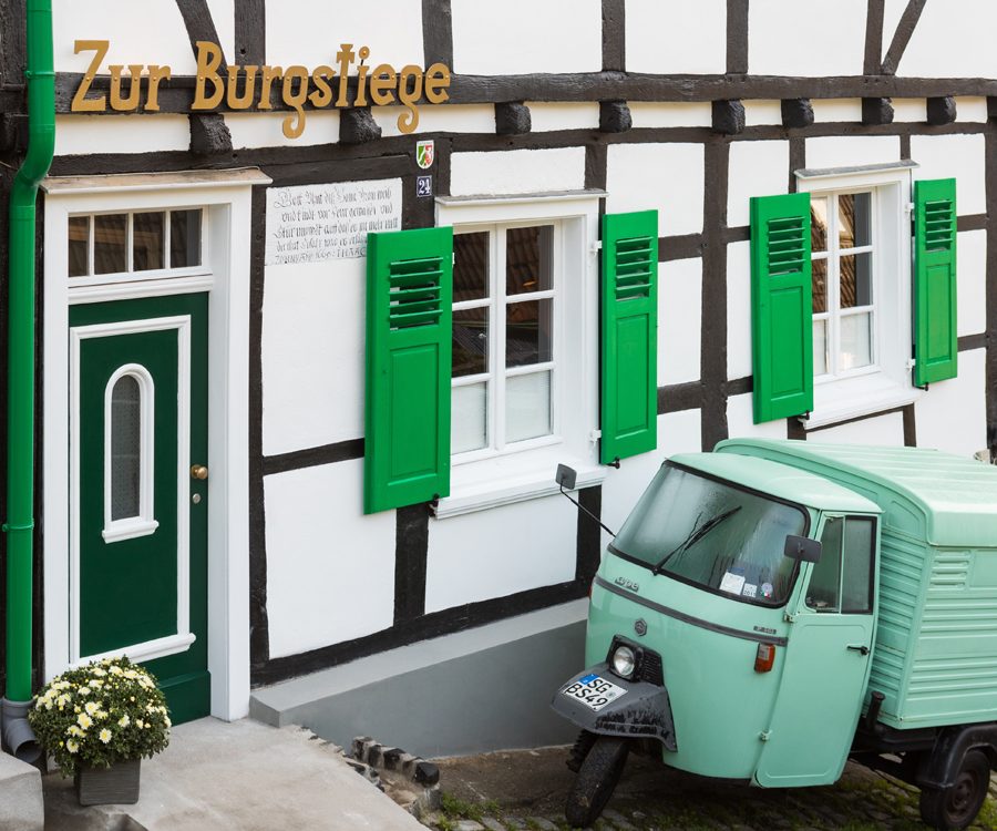 Die mintgrüne Ape vor dem Fachwerkhaus mit grünen Fensterläden