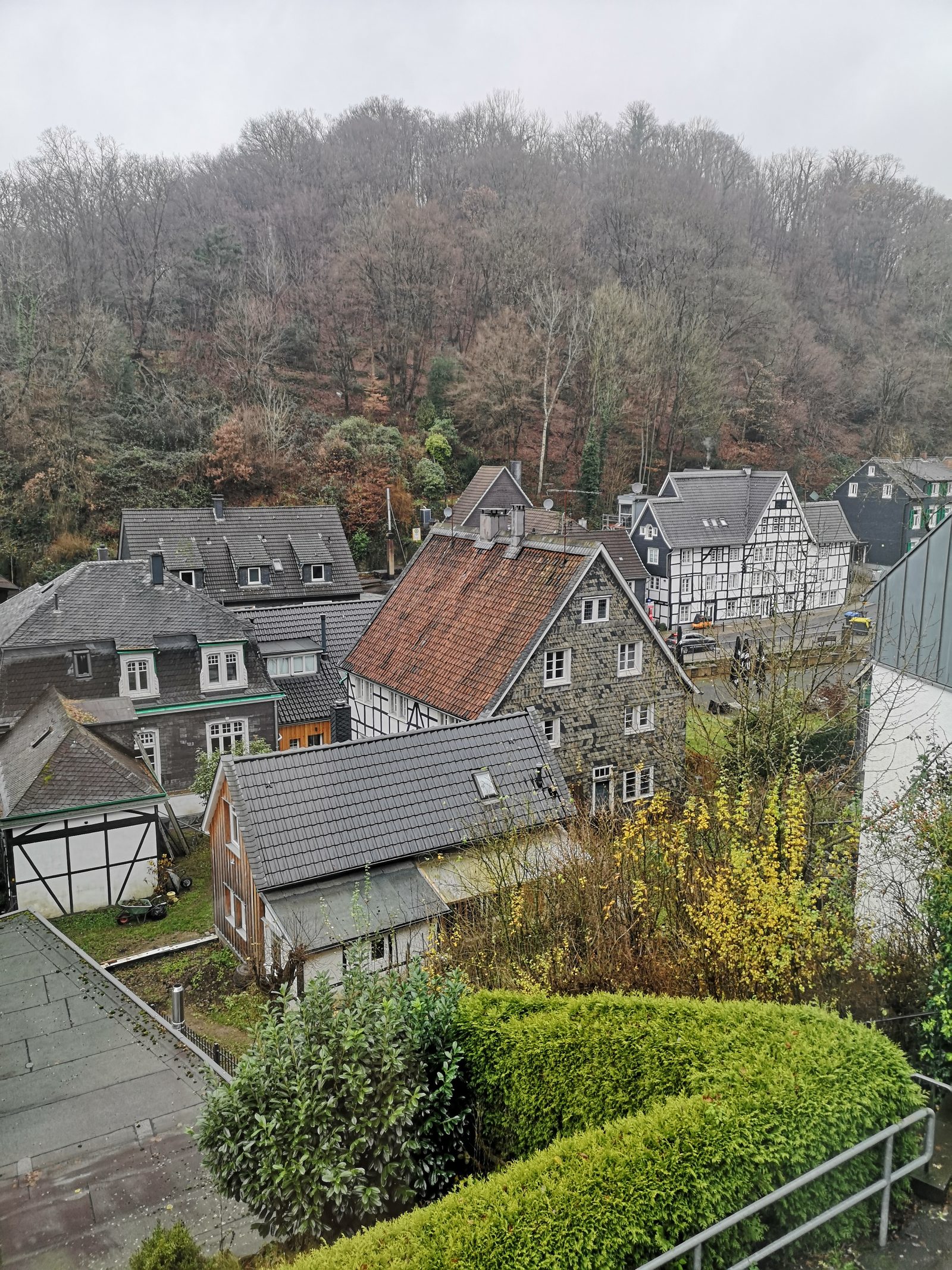 Blick über Fachwerk- und Schieferhäuser von Unterburg, dahinter der bewaldete Hang
