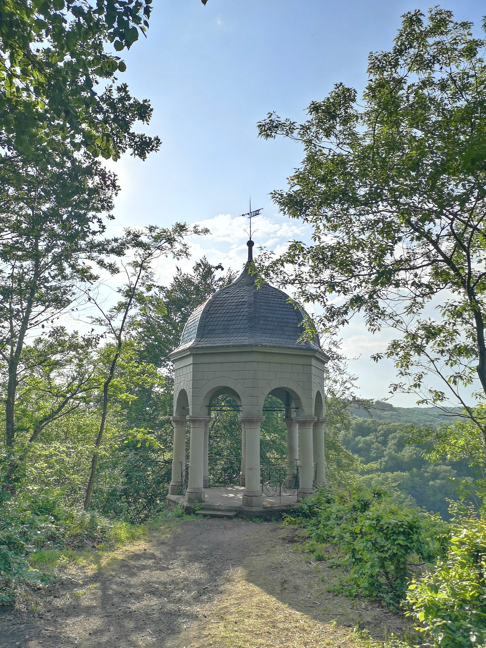 Der Diederichstempel bei Burg, ein achteckiger Pavillon mit Rundbögen und Schieferhaube, zwischen Bäumen
