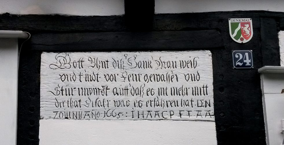 Die Hausinschrift von 1665 im Fachwerk über der Tür, daneben das Denkmal-Schild